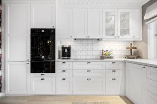 A kitchen with white cabinets and a black oven