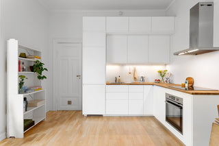 A kitchen with white cabinets and wooden floors