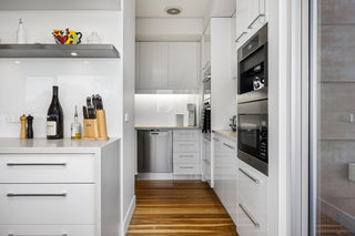 A kitchen with white cabinets and a wooden floor