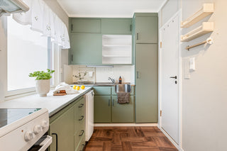 A kitchen with green cabinets and white appliances