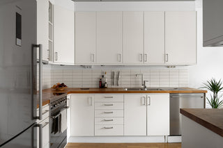 A kitchen with white cabinets and a silver refrigerator